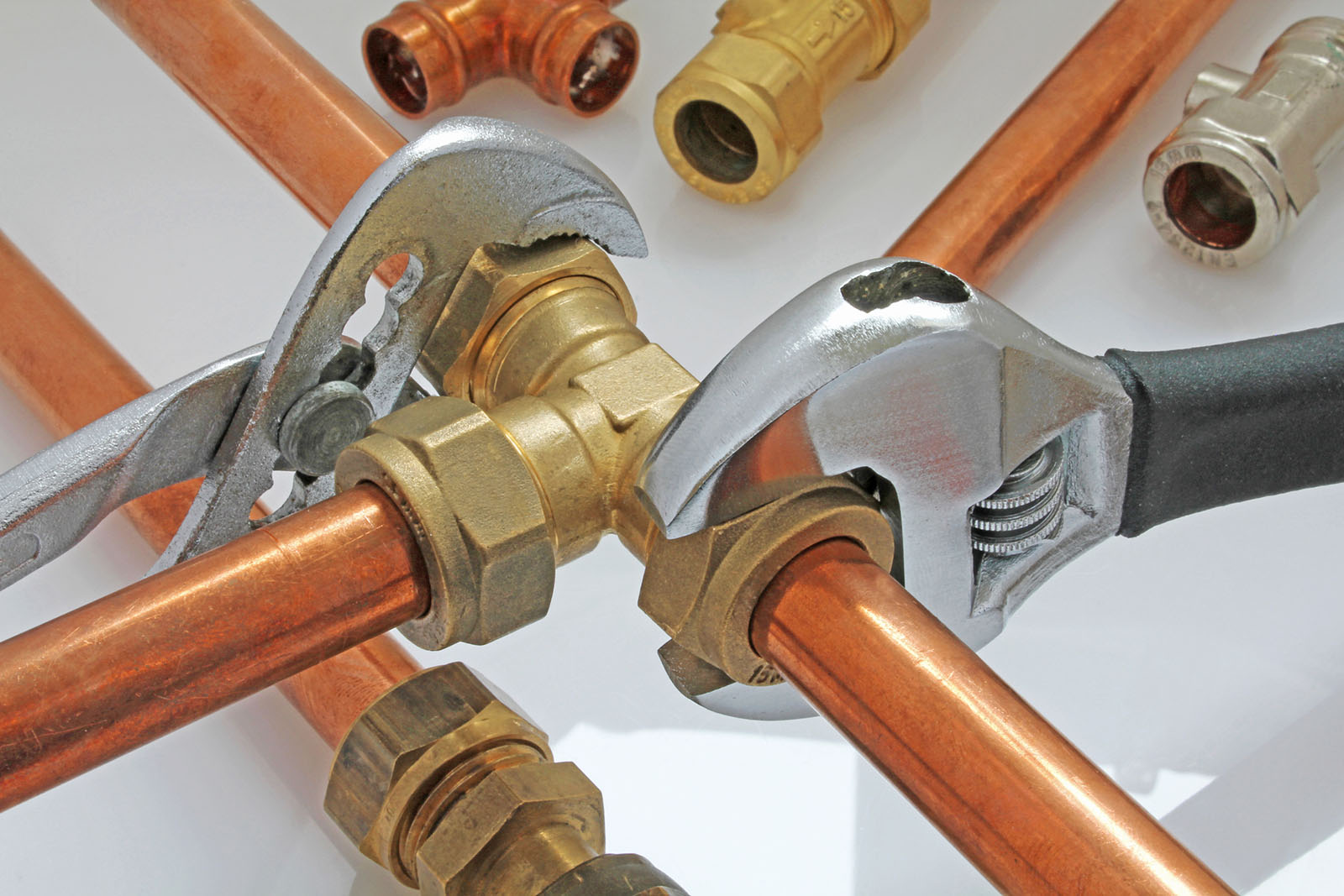 Adjustable wrenches tightening up copper pipe fittings